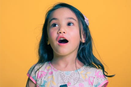 little girl smiles against a yellow background