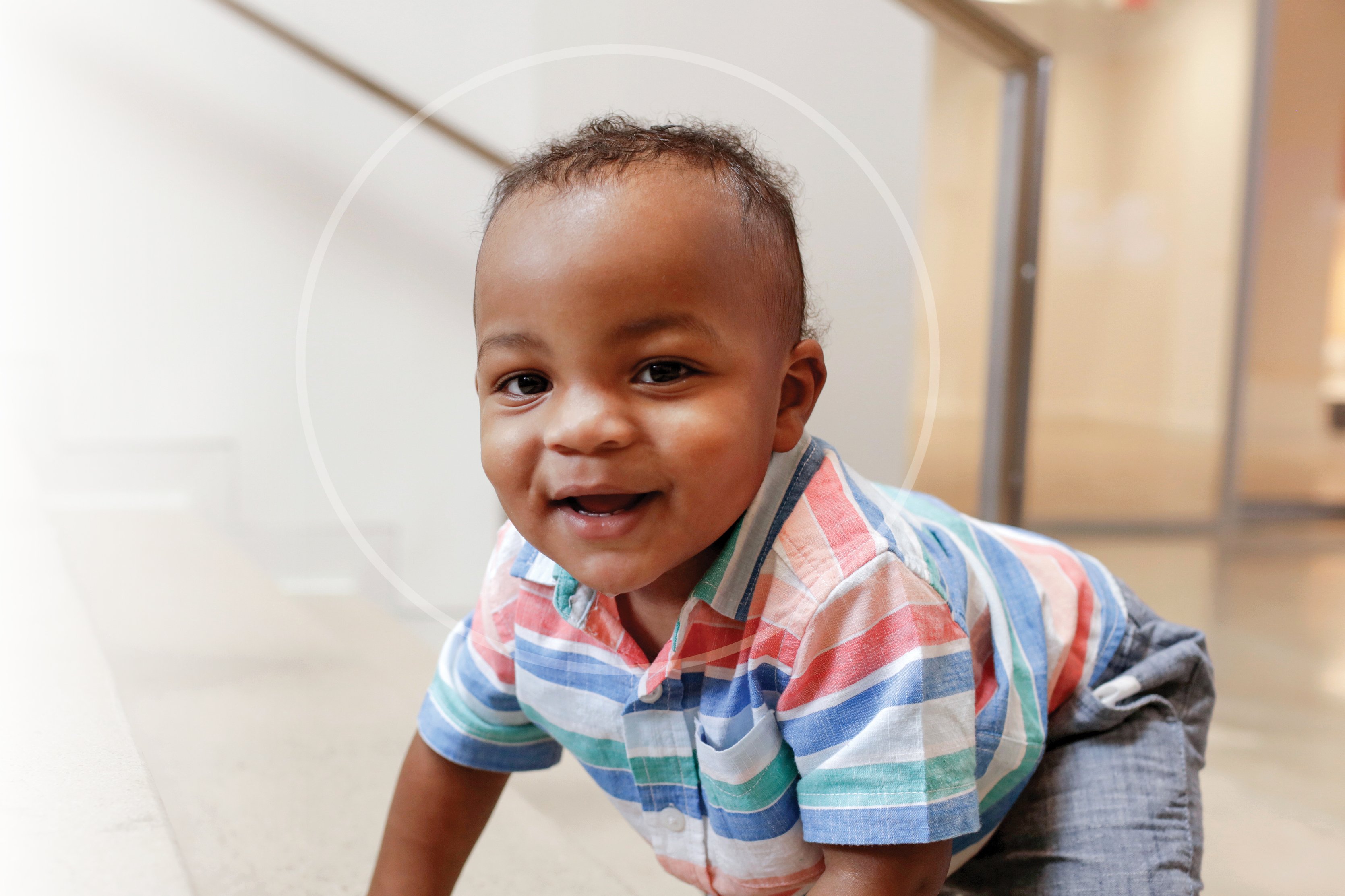 A baby boy of color smiling and crawling