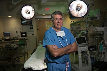 Surgeon standing in empty operating room with arms crossed