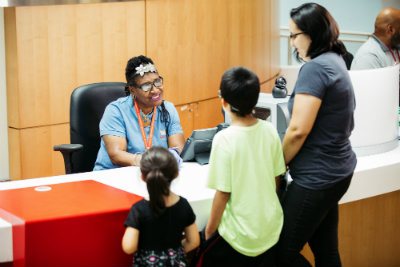 Receptionist sitting at desk talking to a mother, son, and daughter