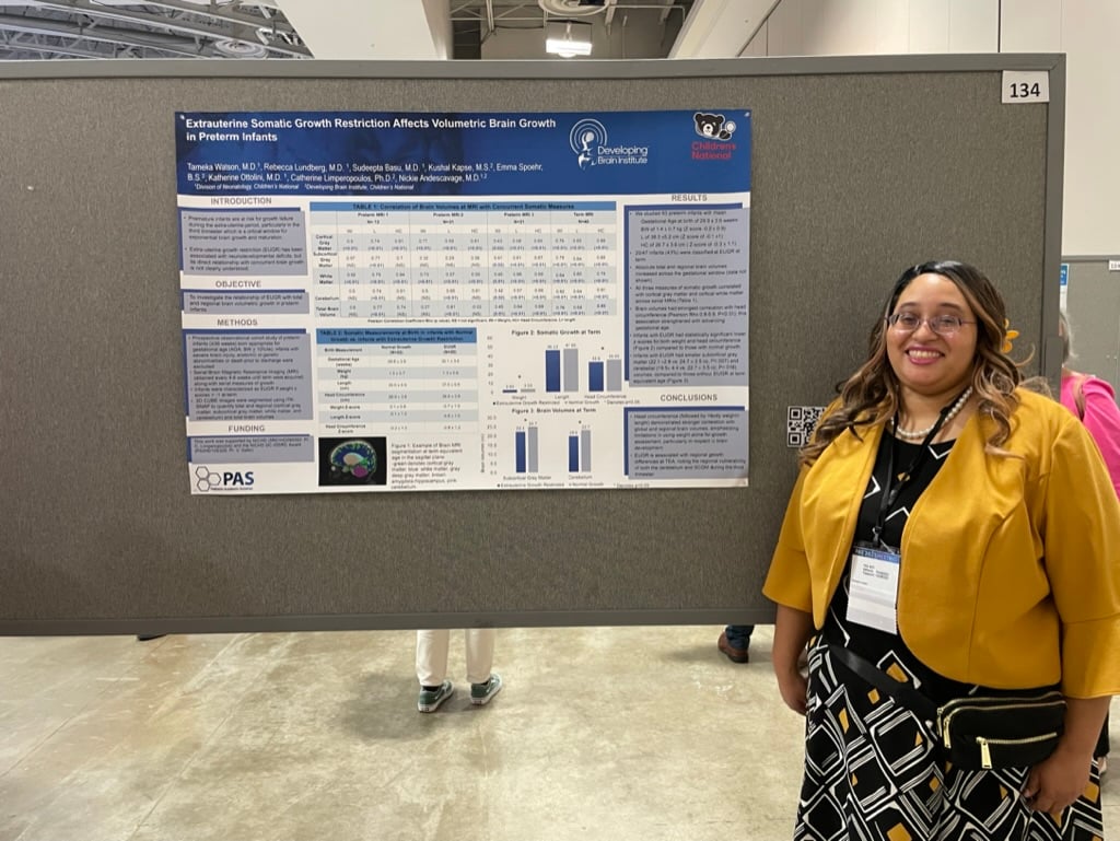 A neonatal-perinatal fellow stands with her poster.