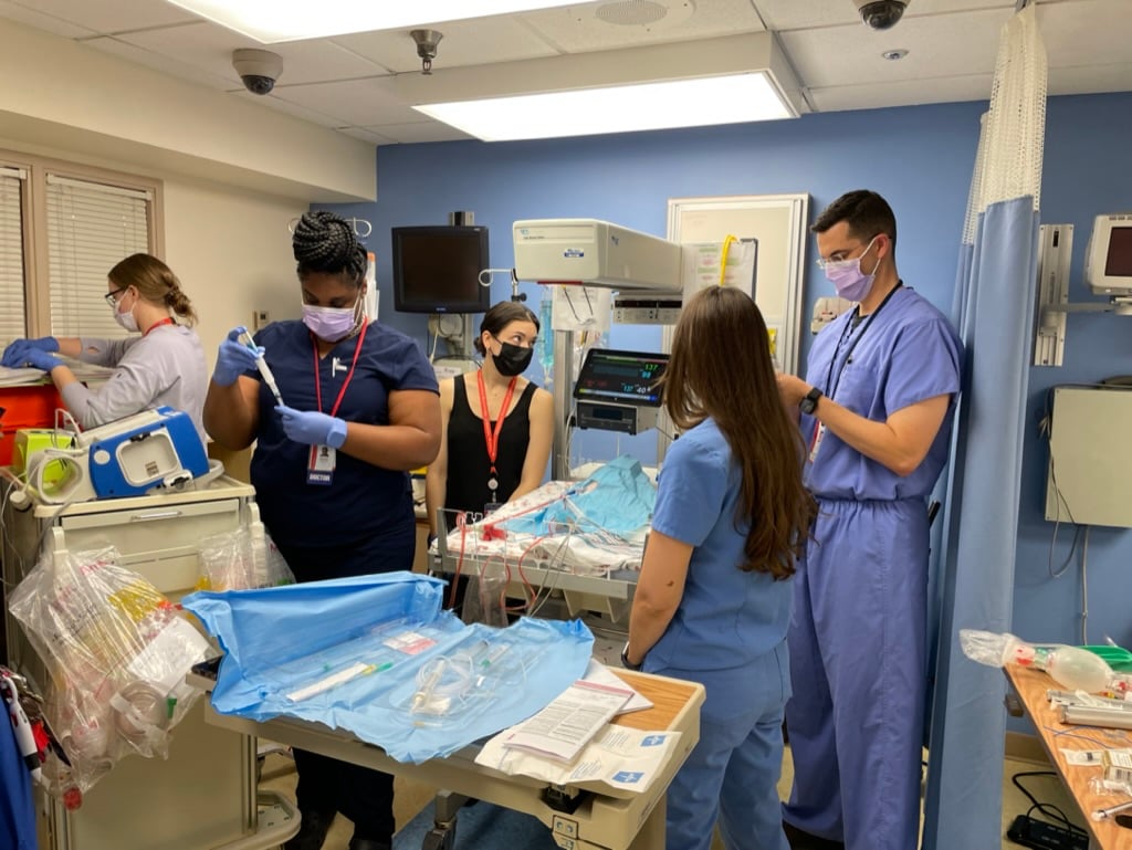 Neonatal-perinatal fellows practicing using medical tools and corresponding with each other.