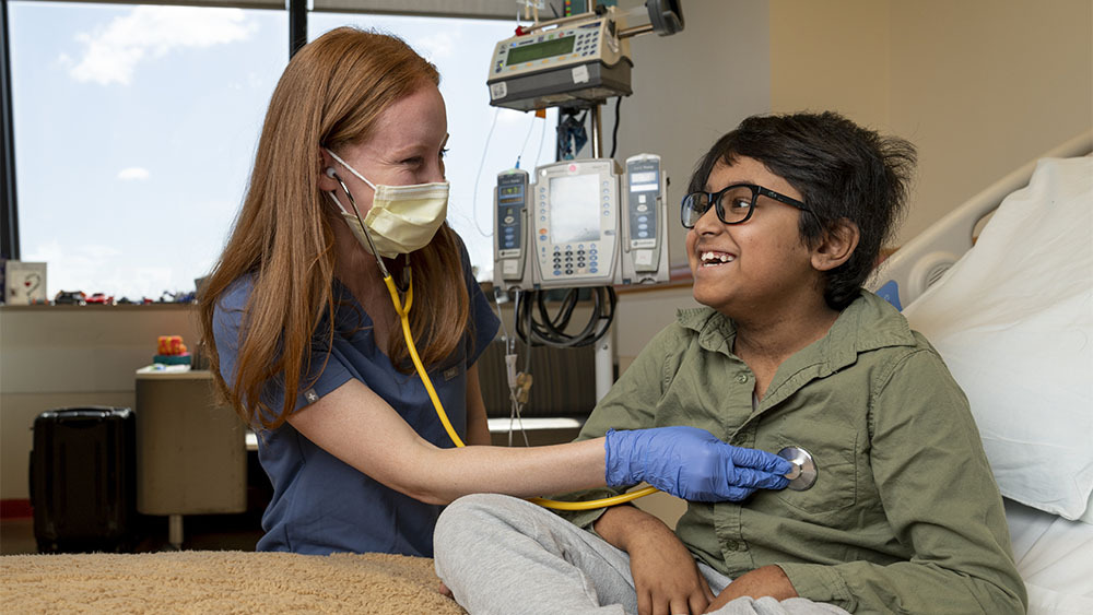 A nurse listens to a boy's heart with a stethoscope