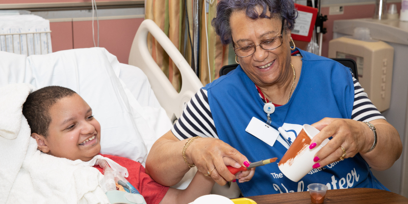 Woman helps young patient paint