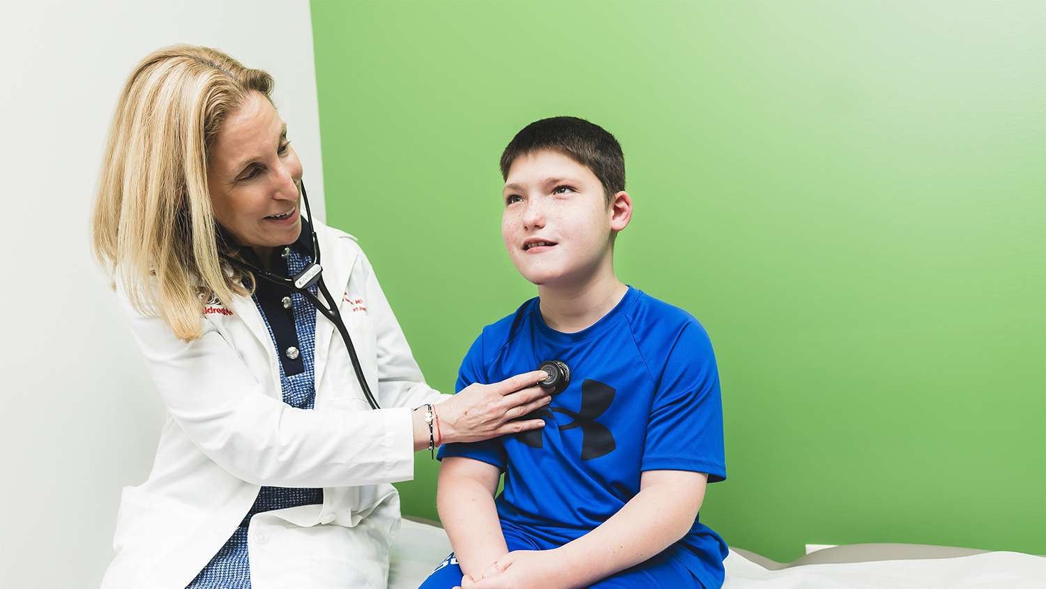 Doctor checking a young boys heart with a stethoscope. 