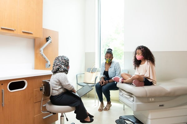 Provider talks to girl and mom in exam room