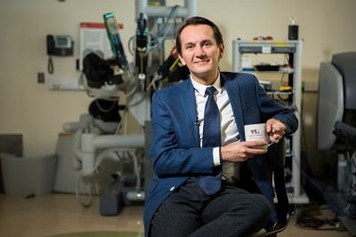 Doctor in a blue suit sitting and holding a Children's National coffee cup