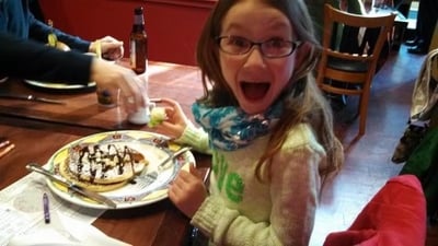 Maia excited to eat pancakes covered in whip cream and chocolate syrup