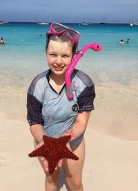 Juliana at the beach holding a starfish and wearing a snorkel