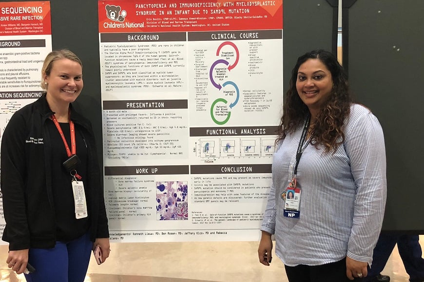 Two female providers stand with a poster at a research presentation.