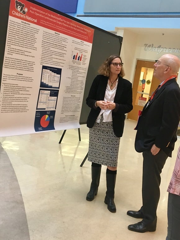Children's National President and CEO Kurt Newman, M.D., looks at a research poster with an advanced practice provider.