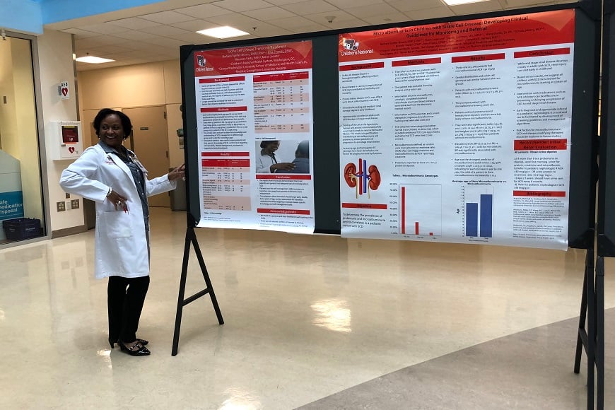 An Advanced Practice Provider with her poster presentation display board.