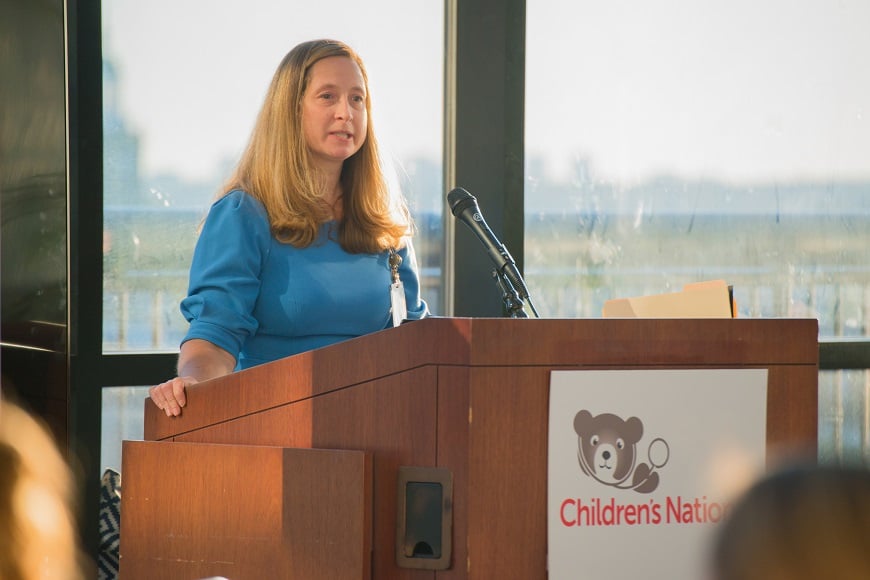 A woman speaks at a podium at an Advanced Practice Provider event.