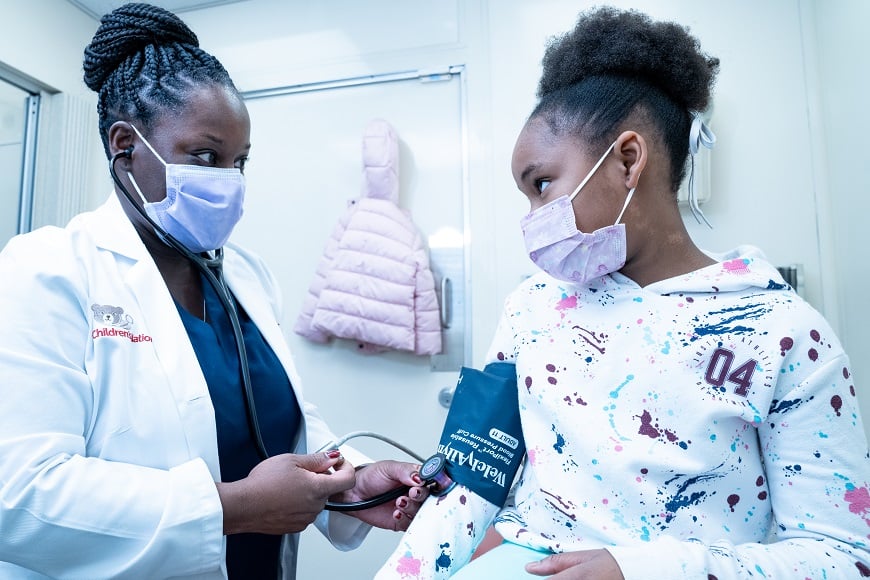 A doctor measures a girl's blood pressure in the mobile health van.