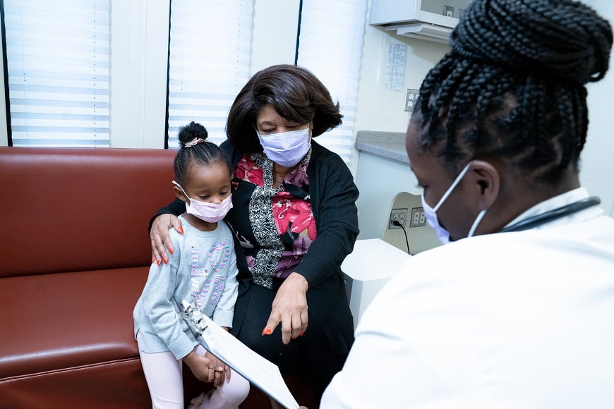 A doctor sits down to meet with a mother and daughter in the mobile health van.