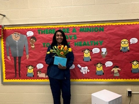 Rose Moore standing in front of a red school bulletin board