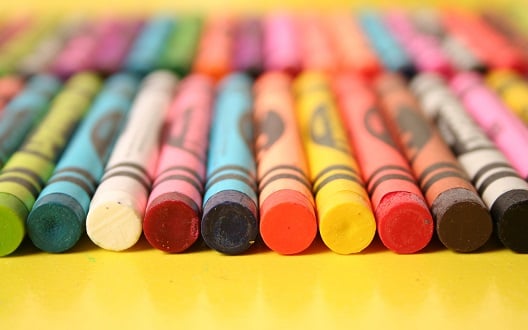 A closeup image of a variety of crayons on a yellow table