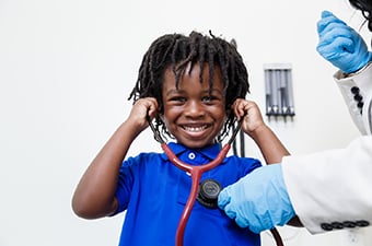 Child with dreadlocks playing with a stethoscope