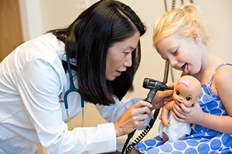 Doctor examining a young girl's doll