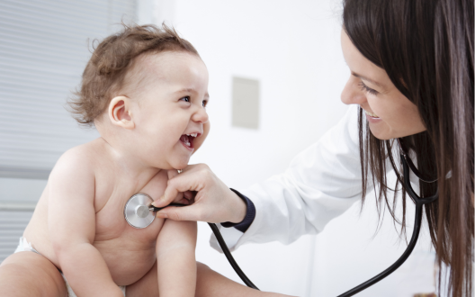 smiling baby being examined by doctor