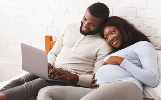 pregnant woman and her partner looking at laptop