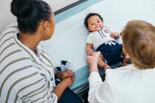 Infant on exam table with Mom and pediatrician