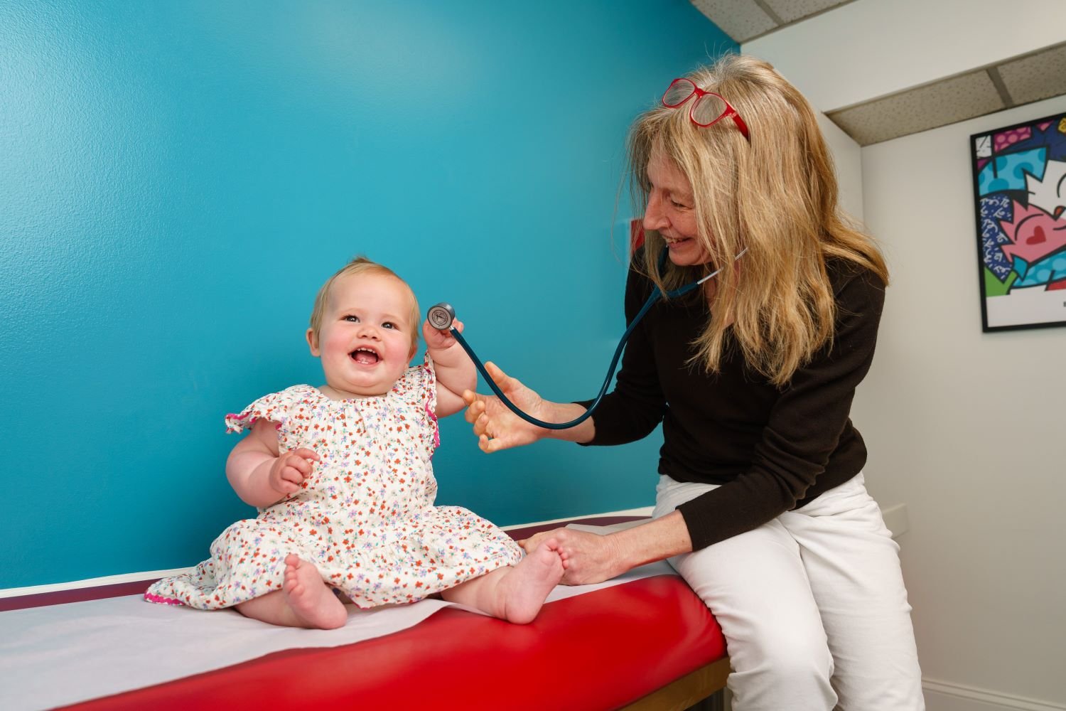 doctor examines smiling baby girl 