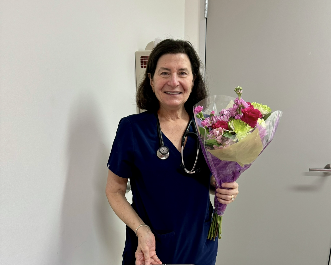 Dr. Judy Ratner holding flowers at her retirement
