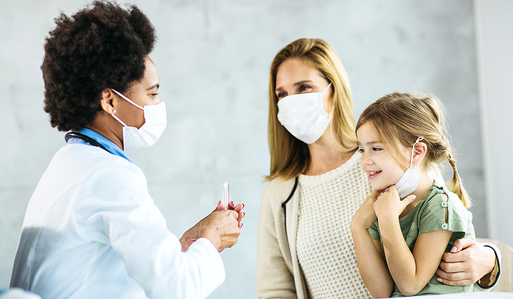 Doctor holding PCR test in front of mother and daughter