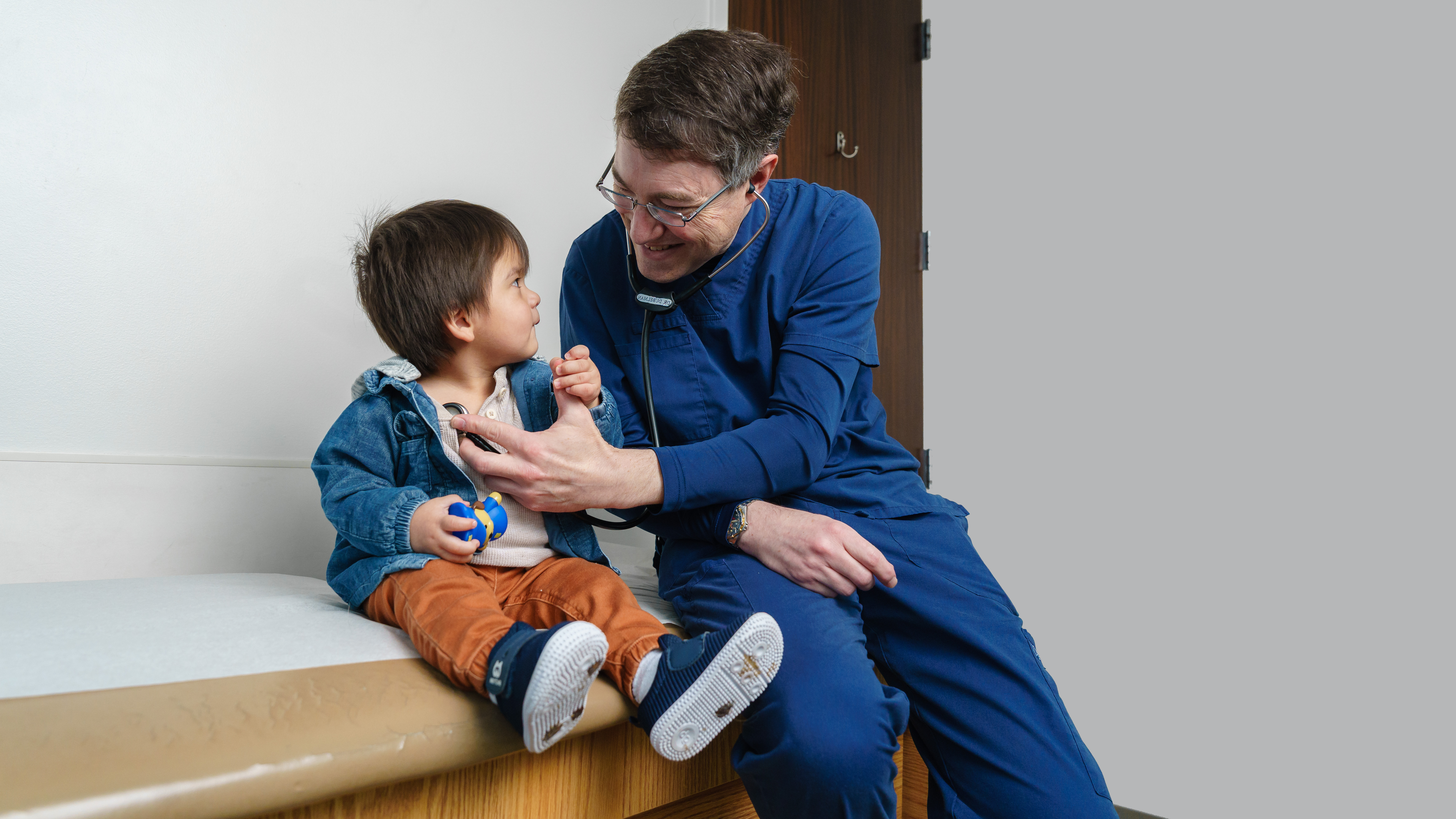 Provider examining toddler boy on exam table