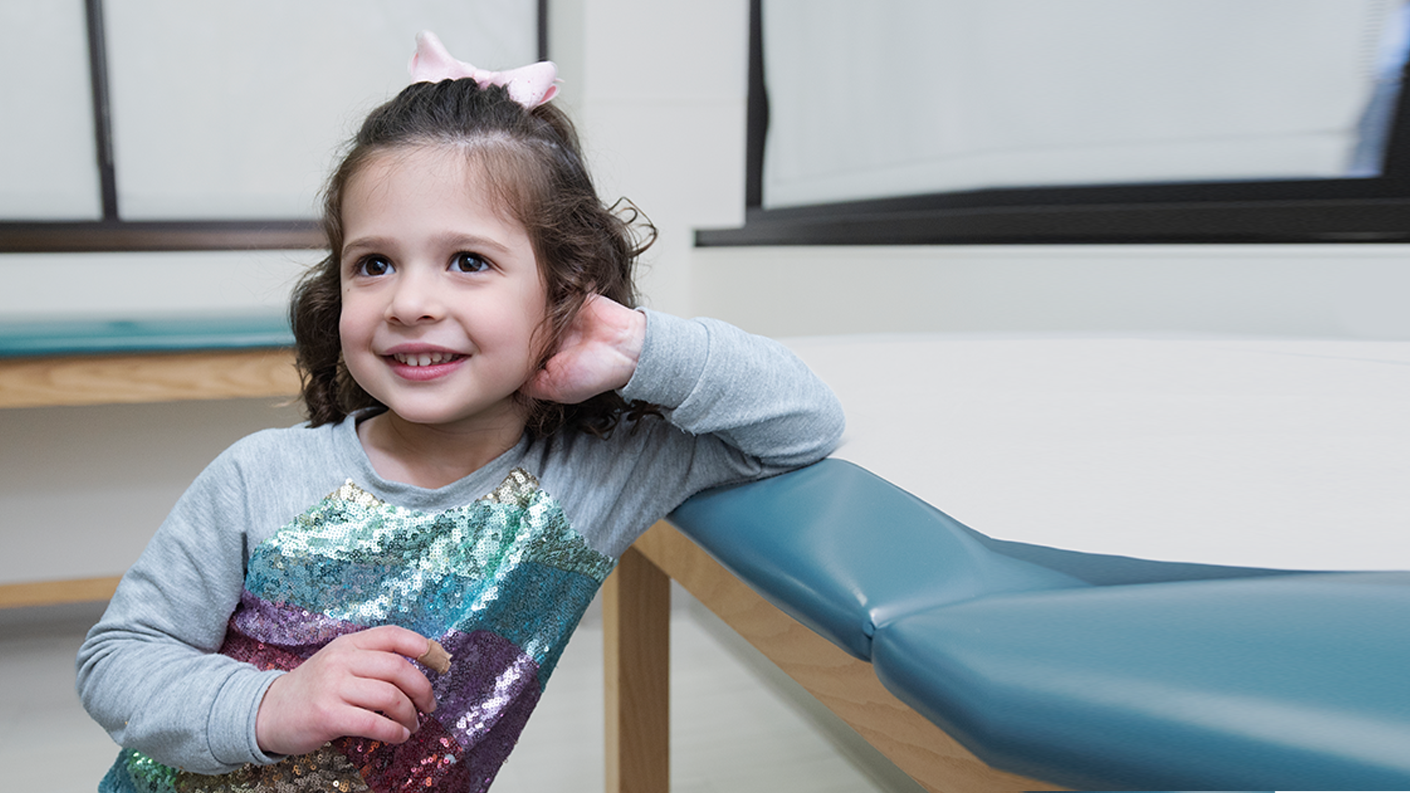 smiling young girl leaning on exam table