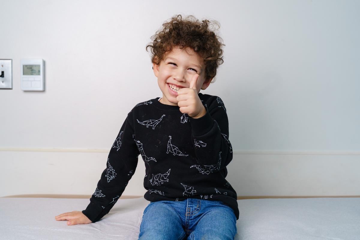 Smiling boy sitting on exam table giving thumbs up