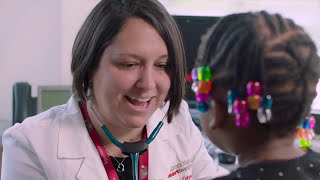 Female provider using a stethoscope on a little girl with hair beads