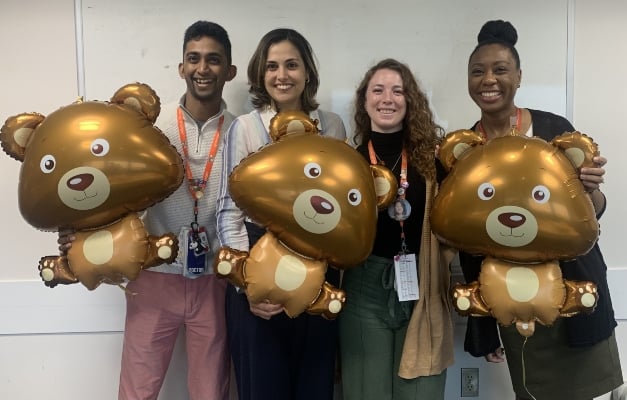 Group photo of healthcare residents holding gold bear balloons