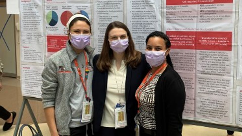 Residents in front of their research poster wearing masks