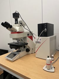 White, black and red upright epifluorescence microscope.