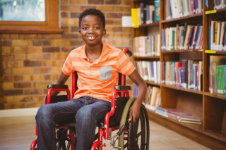 Boy in wheelchair in front of bookshelf