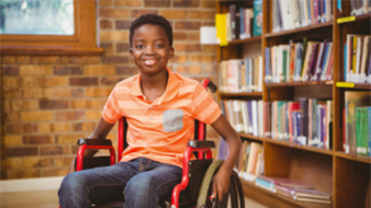 Boy in wheelchair in front of bookshelf