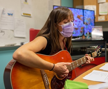 A music therapist plays guitar in the comfort corner