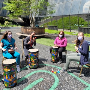Healthcare providers play drums in a circle in the Healing Garden