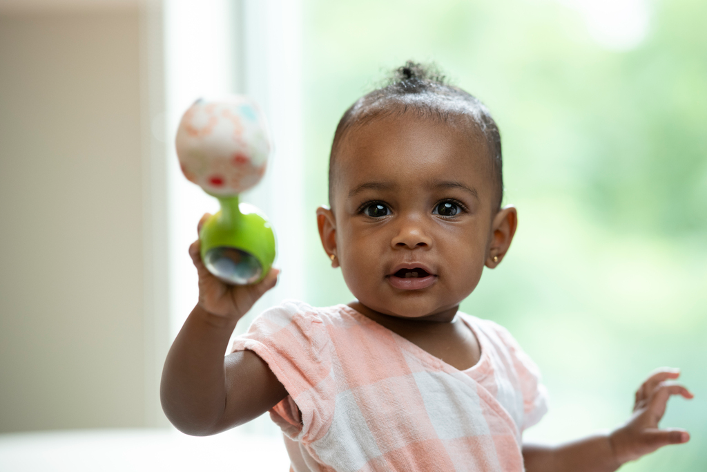 A baby girl holding a rattle