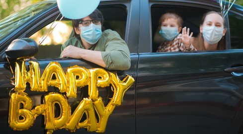 A family sitting in a vehicle decorated with happy birthday