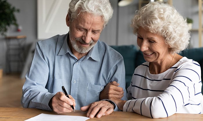 Senior man and woman signing a document