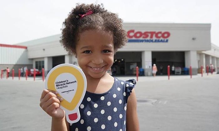 A girl holding miracle network sign in front of Costco