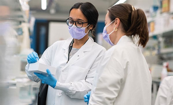 Two female researchers confer in the lab.