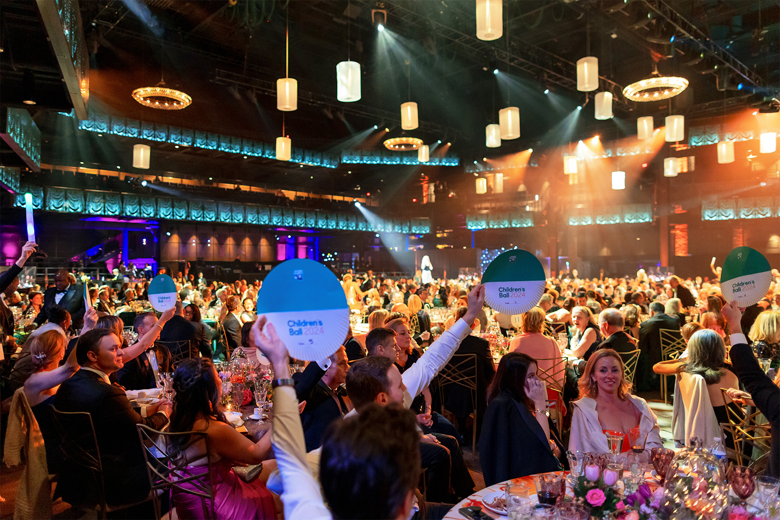 Children's ball guests holding up auction paddles.