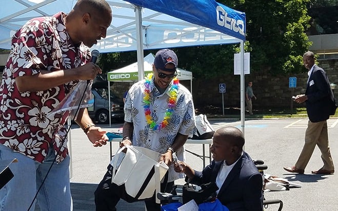 GEICO staff present a fellow employee with a swag bag at a company giving event.