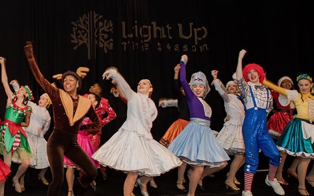 Performers in a variety of Christmas costumes dance on stage at the Light Up the Season fundraiser.