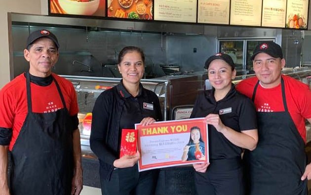 Panda Express staff members hold a donation check at their restaurant.