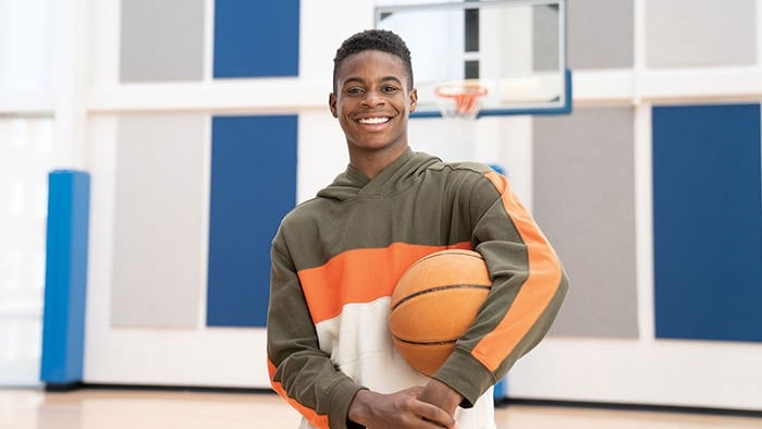 Young patient holding basketball in a gymnasium.